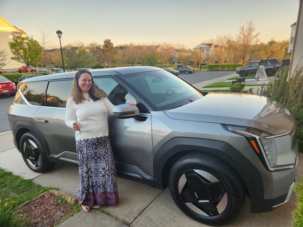 Mary Beth proudly stands by her new Kia EV9 in 2025. 